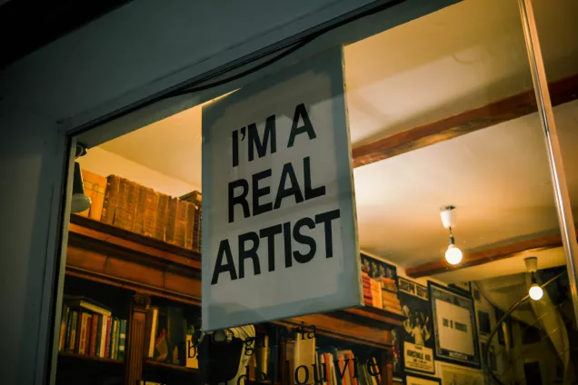 Foto som visar ett skyltfönster till ett antikvariat där det hänger en skylt med texten "I'm a real artist".